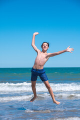 Happy boy performs pirouettes and big jumps on the seashore during his summer vacation on the Atlantic Coast, Las Grutas, Rio Negro, Argentina. © buenaventura13