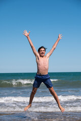 Happy boy performs pirouettes and big jumps on the seashore during his summer vacation on the...