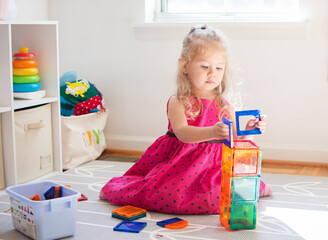 Little child playing with magnet tiles. Toddler caucasian girl playing.	