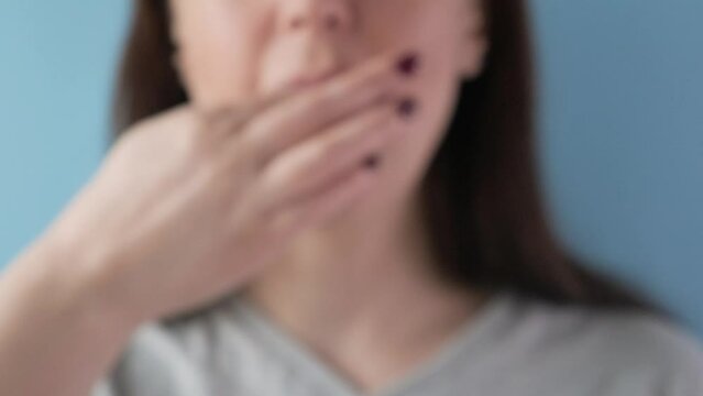 Woman taking white pill of statin medicine to treat high cholesterol or painkiller with glass of water on blue background