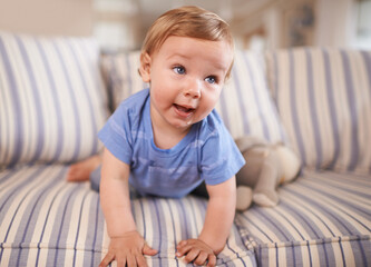 The cutest smile. an adorable little infant sitting on a sofa.