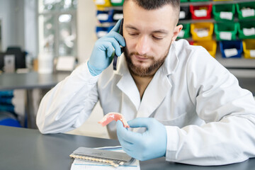 Portrait of Dental technician or dentist in his laboratory call to doctor or patient.