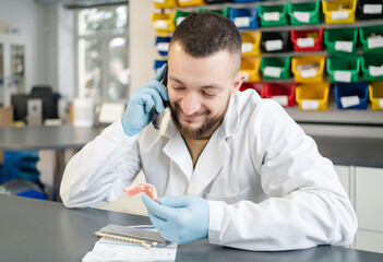 Portrait of Dental technician or dentist in his laboratory call to doctor or patient.