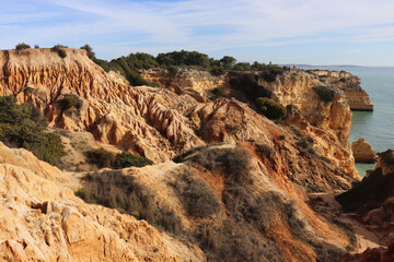 Fototapeta na wymiar Orange limestone cliffs next to the Atlantic Ocean along the Seven Hanging Valleys hiking path in Algarve, Portugal.