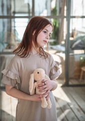 Cute girl with a toy hare in her hands looking at the camera and smiling