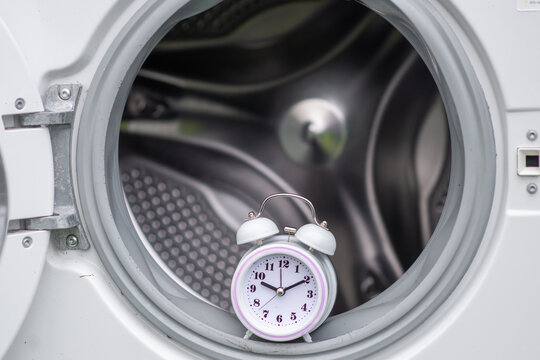 time and washing machine. Waiting, washing duration concept. Open door of washing machine and alarm clock.