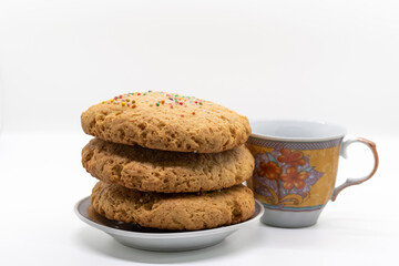 Stack of cookies on a plate next to a coffee cup, selective focus