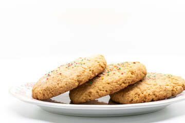 Stack of cookies with colored sprinkles on plate, selective focus, copy space, product