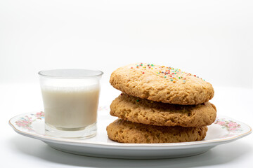 Biscuits next to a cup of milk on a long plate isolated white background selective focus