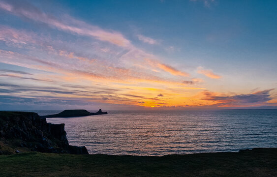 Wales Swansea, UK. Dragon's Rest: A Majestic Worm's Head Sunset in Wales.