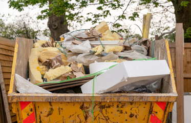 Yellow industrial metal skip full of construction rubbish ready for collection
