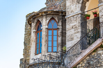 Old medieval castle with long windows and a staircase surrounded by wrought iron