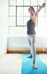 Obraz premium Strengthen and lengthen those muscles through yoga. an attractive young woman practising yoga at home.