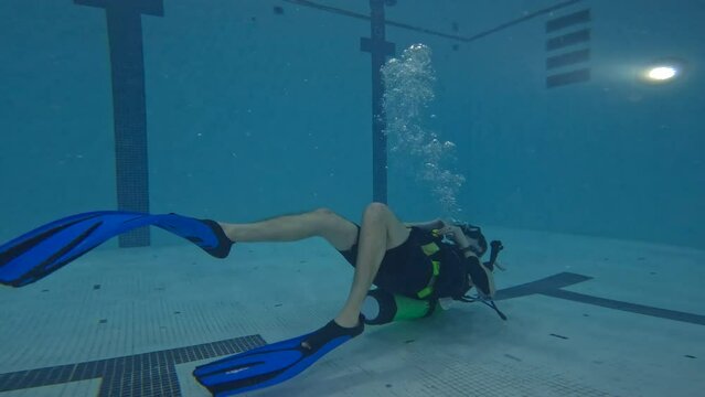 Scuba diver training upside down at bottom of swimming pool