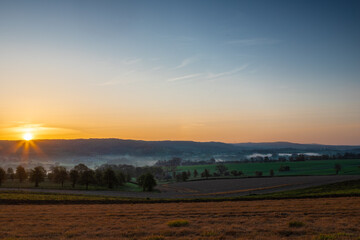 Colourful sunrise on a summer morning with a little fog on the ground and spectacular views over the Dutch hillside near the village of Kuttingen