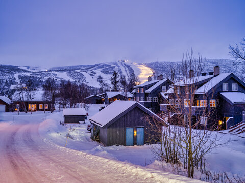 Wooden Norwegen houses and Ski Run in the background litp up after sunset in Geilo, Norway