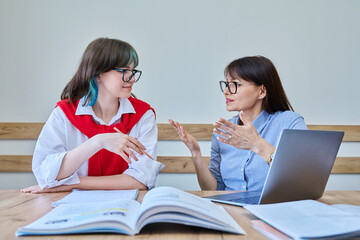 College student girl sitting with female teacher studying individually in class