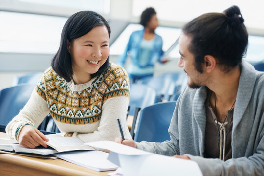 Friendly Classroom Banter. A Two University Students Talking To Each Other In A Lecture Hall.