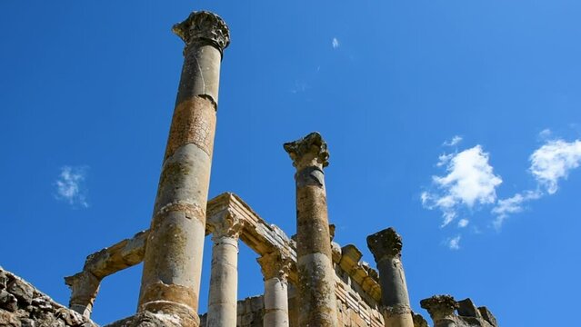 Low-angle view of Roman columns against a blue sky in the ancient city of Cuicul-Djemila. UNESCO world heritage site. Setif, Algeria