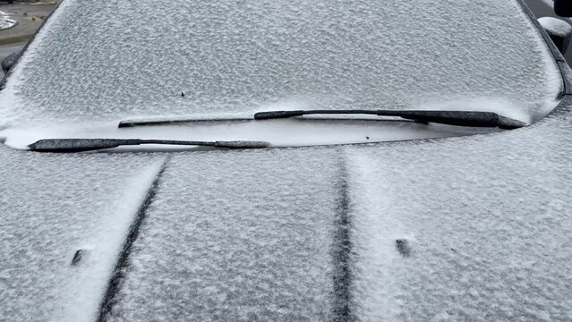 After wet snow and frost at night, the car body and windshield are covered with a layer of ice and snow. The car froze after overnight parking on the street in winter. The car is covered with ice afte