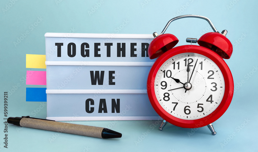 Poster text together we can written on the lightbox with alarm clock and colorfull stickers on blue backgro