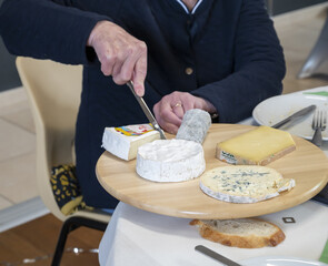 Obraz na płótnie Canvas homme âgé se servant sur un plateau de fromages français