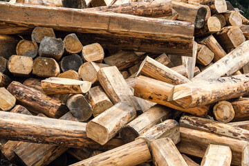 A pile of chopped wood for a fire as a background. Chopped tree trunks are thrown in a chaotic order on top of each other in close-up.