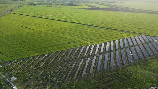 An aerial view of solar panels set amidst a desert landscape. The rugged terrain and clear blue skies provide a stunning backdrop for the panels, which stand as a beacon of hope in an otherwise harsh