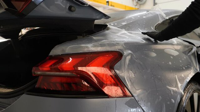 Close up to PPF installation process on a front headlight and hood. PPF is a Paint Protection Film which protect paint from scratches and stone chips. Concept of: Guard, Protect, Car, New, Work.	
