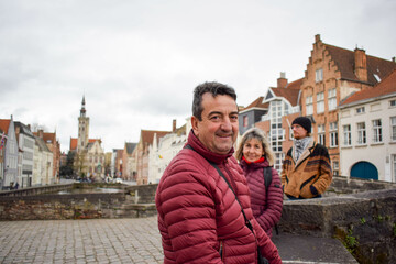 Naklejka premium Caucasian family on bridge in Bruges town, Belgium. Adult couple, turist walking on the canal, posing for the picture.