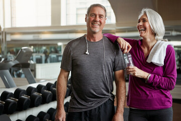Great marriages start with great fitness. a senior married couple laughing and taking a break from their workout at the gym.