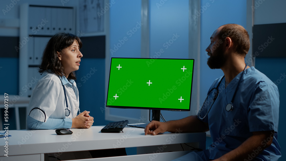Poster medic and assistant looking at computer monitor with green screen chroma key isolated display while 