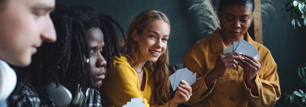 Diverse group of young people, friends, college students gathering together, have fun, playing games, laughing. Concept of diversity, international friendship, learning foreign languages banner