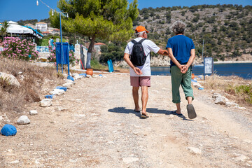 Two male tourists walking on the Kastos island, Greece in summer sunny day.
