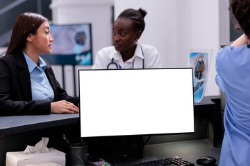 Computer with white screen standing on reception counter desk in hospital waiting room while...