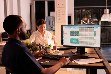 African american man analyzing fund market investment data on computer screen in coworking space,...