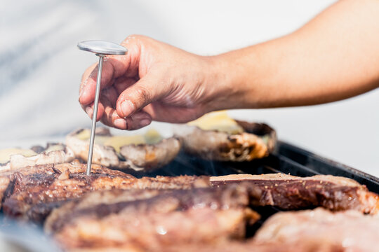 grilled meat on a grill with thermometer and a cheff´s hand