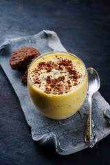 Traditionelles Sanddorn Orange Mousse mit Keksen und Streusel serviert als close-up in einem classic Design Glas