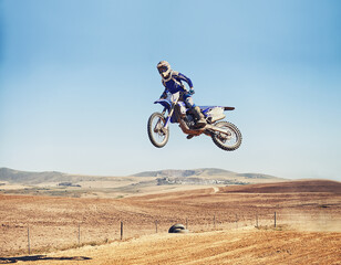 Fototapeta na wymiar Going over a jump with style. a motocross rider in midair after hitting a jump.