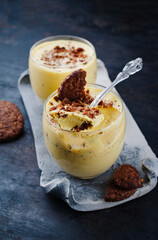 Traditionelles Sanddorn Orange Mousse mit Keksen und Streusel serviert als close-up in einem classic Design Glas