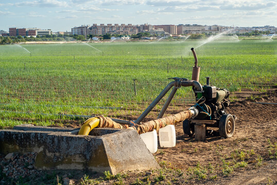 Motor extrayendo agua de un canal de riego y transportandola hacia los aspersores en el campo de cultivo.