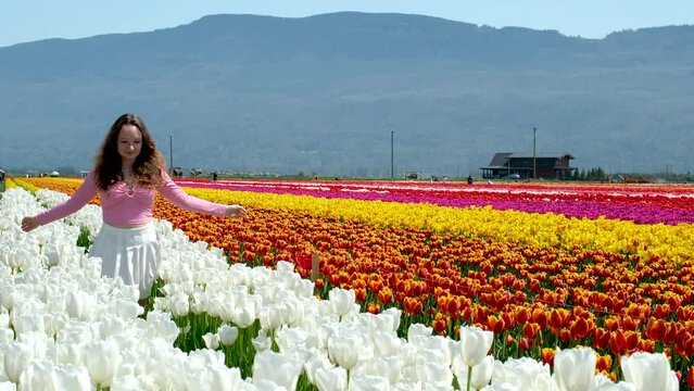 beautiful young girl teenager woman runs across white field of tulips snow-white flowers touch legs white Tennis skirt develops hair against backdrop mountains nature Freedom virginity cleanliness ad