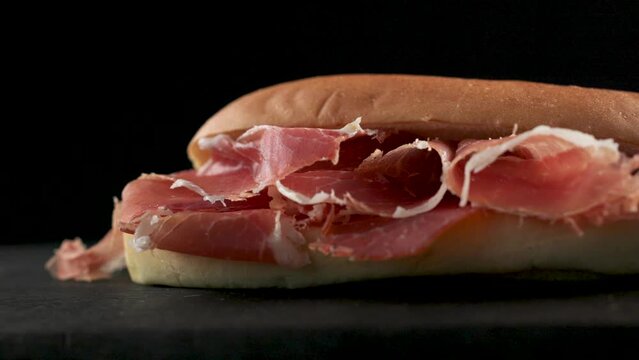 sandwich with sliced spanish iberico ham on black wooden board