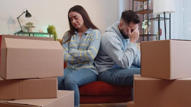 Upset depressed family married couple man woman at home room on sofa near cardboard stuff boxes. Sad husband wife tired of long relocation, bankruptcy, bank house loan debt, divorce, crisis concept