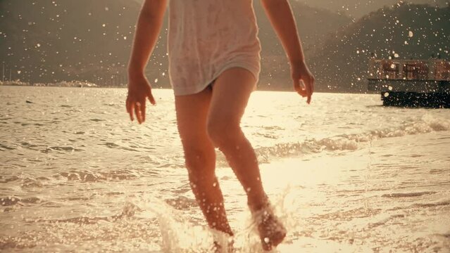 Little girl runs barefoot on the sand beach, close-up slow motion