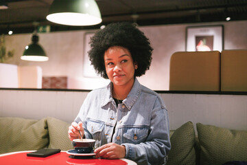Fototapeta na wymiar afro woman drinking coffee in a cafe, close up view
