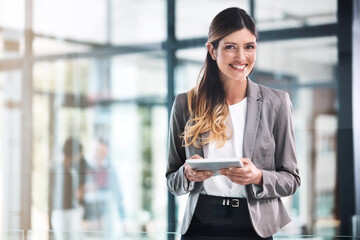 I never do business without it. Portrait of a young businesswoman using a digital tablet in a...