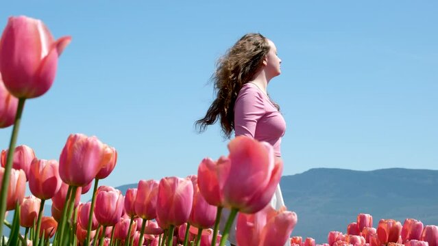 young teen woman stands in polis with pink tulips look into distance look into future look into nowhere Freedom purity freshness wind develop in wind Real beauty freshness spring Youth virginity dream