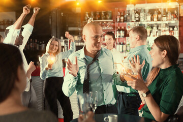 Man in unbuttoned shirt and untied tie drinking alcohol and having fun at corporate party