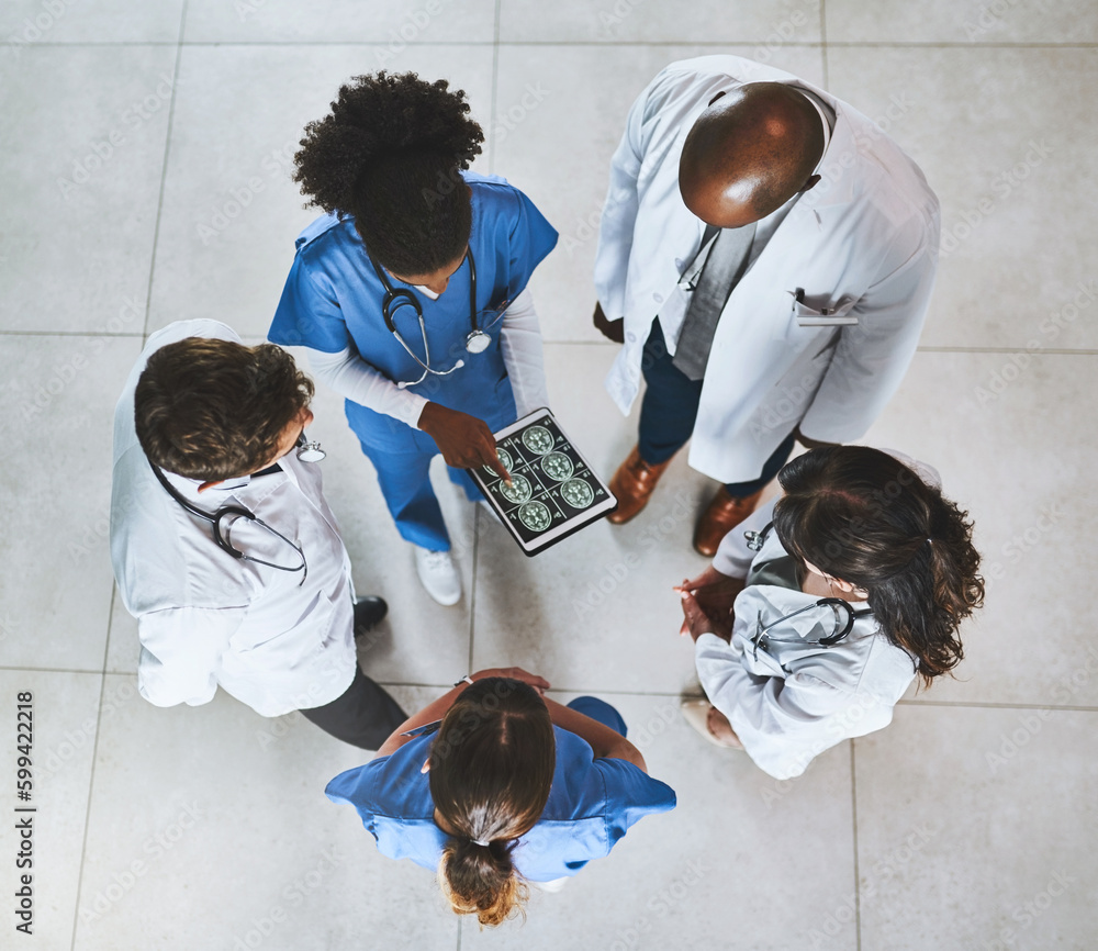 Poster developing a life saving strategy. high angle shot of a team of doctors using a digital tablet to di